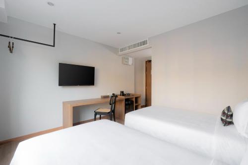 a bedroom with two beds and a desk with a tv at Pranakorn Heritage Hotel in Bangkok