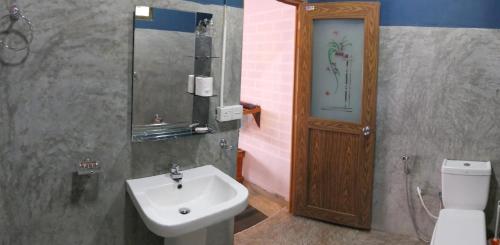 ein Bad mit einem Waschbecken, einem WC und einer Tür in der Unterkunft Summer Villa Ella in Ella