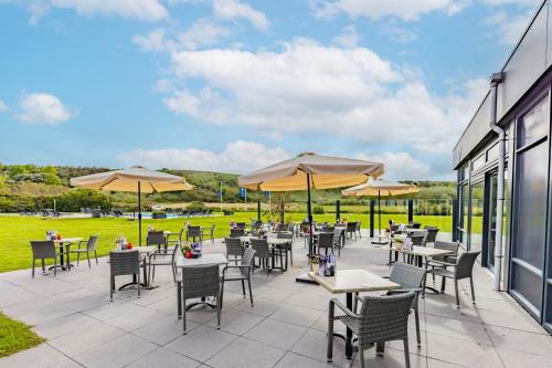 a patio with tables and chairs and umbrellas at Fletcher Zuiderduin Beachhotel in Westkapelle