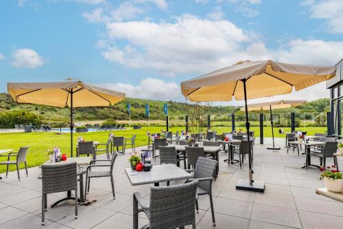 a patio with tables and chairs and umbrellas at Fletcher Zuiderduin Beachhotel in Westkapelle
