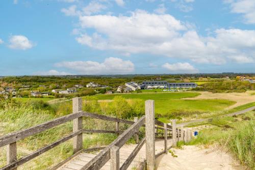 a wooden fence in a field with a house in the background at Fletcher Zuiderduin Beachhotel in Westkapelle