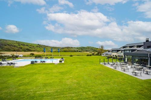 a resort with a pool and tables and chairs at Fletcher Zuiderduin Beachhotel in Westkapelle