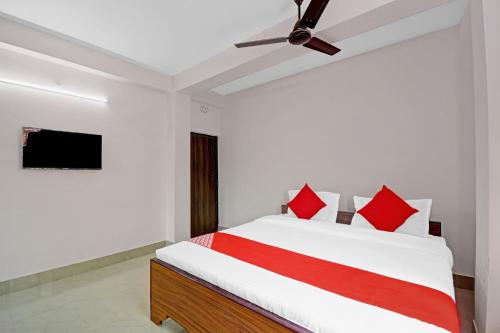 een slaapkamer met een bed met rode kussens en een plafondventilator bij OYO Hotel Grand Eden in Calcutta