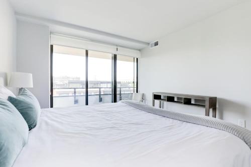 a white bedroom with a large bed with a window at 2BR Executive Apartment in Prime Location in Arlington