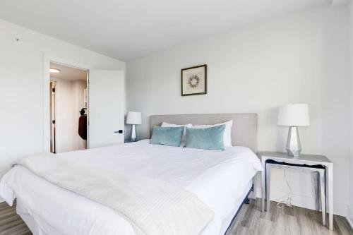 a white bedroom with a large white bed with blue pillows at 2BR Executive Apartment in Prime Location in Arlington