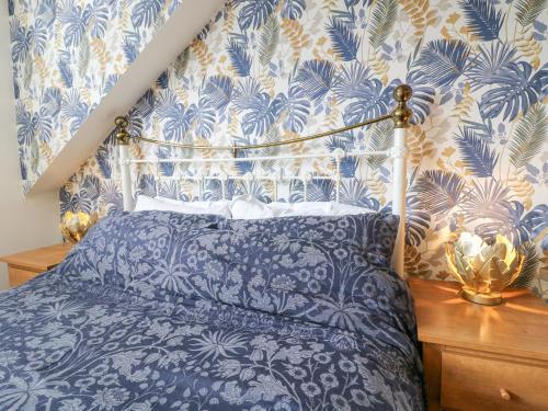 Un dormitorio con una cama con papel pintado azul y blanco. en Matlock Maisonette, en Matlock