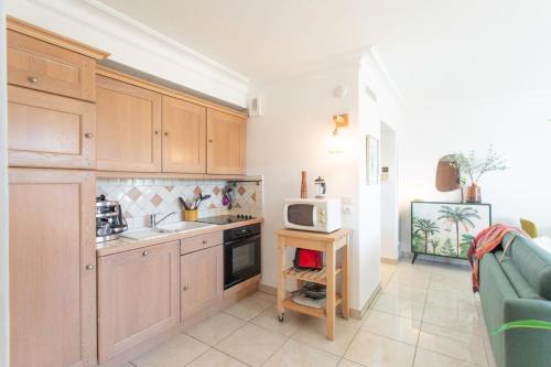 a kitchen with wooden cabinets and a microwave at A13 - 1 BDR Garden floor Fontonne - AC, Pool & Parking in Antibes