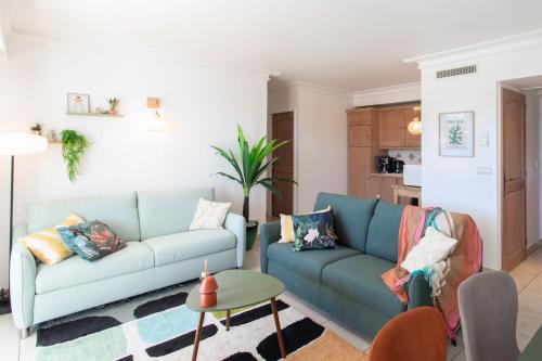 a living room with a blue couch and a table at A13 - 1 BDR Garden floor Fontonne - AC, Pool & Parking in Antibes