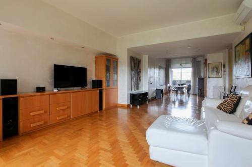 a living room with a white couch and a flat screen tv at FieraMilano 3BR Apartment in Milan