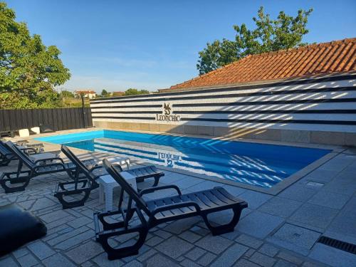 a swimming pool with lounge chairs next to a house at Leonchic - Guest House com Piscina de Água Salgada in Barcelos