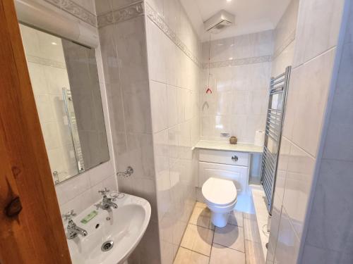 a white bathroom with a sink and a toilet at Beachcombers Apartments in Newquay