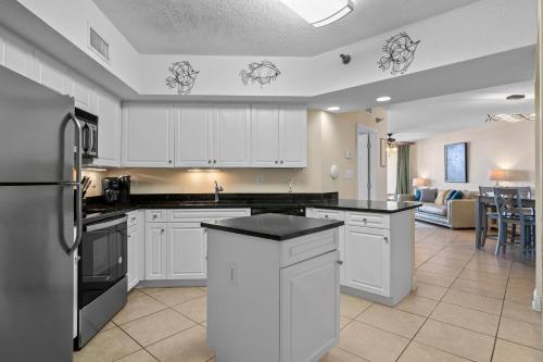 a kitchen with white cabinets and a living room at Bluewater Unit 104 in Orange Beach