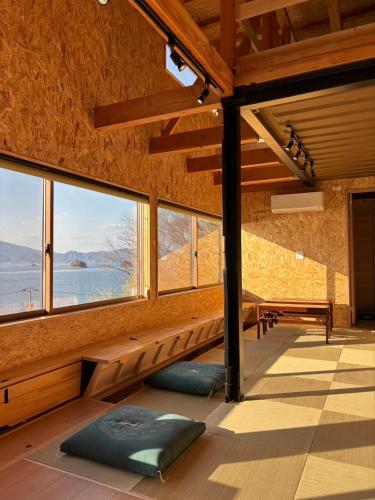 a room with large windows with a table and a bench at nagi-setouchi in Kure