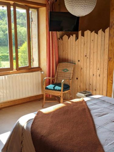 une chambre avec un lit, une chaise et une télévision dans l'établissement Maison du Tertre, à Urval