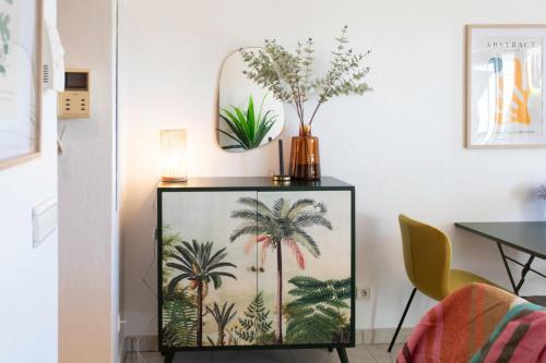 a cabinet with a painting of palm trees on it at A13 - 1 BDR Garden floor Fontonne - AC, Pool & Parking in Antibes