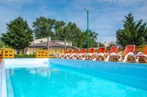 - une piscine avec des chaises rouges et de l'eau bleue dans l'établissement Voila Mamaia, à Mamaia