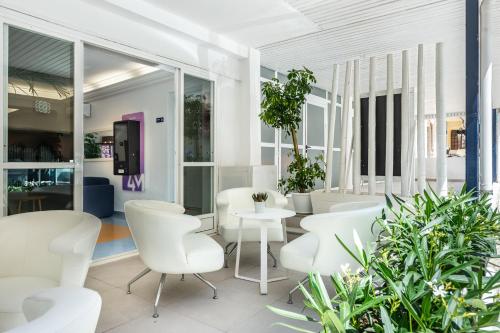 um quarto com cadeiras brancas, mesas e plantas em Hotel Vibra Vila em Cidade de Ibiza