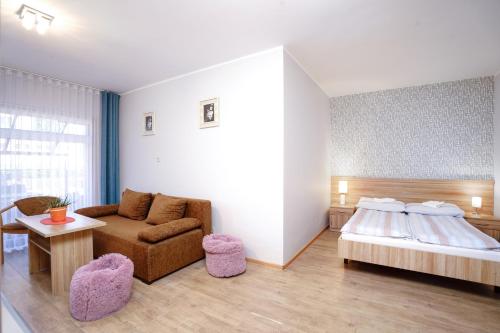 a bedroom with a bed and a couch and a table at Willa Karawela in Łeba