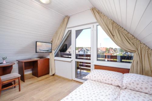 a bedroom with a bed and a desk and a window at Willa Karawela in Łeba