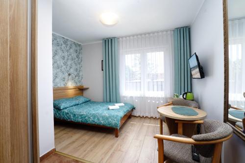 a small room with a bed and a table at Willa Karawela in Łeba