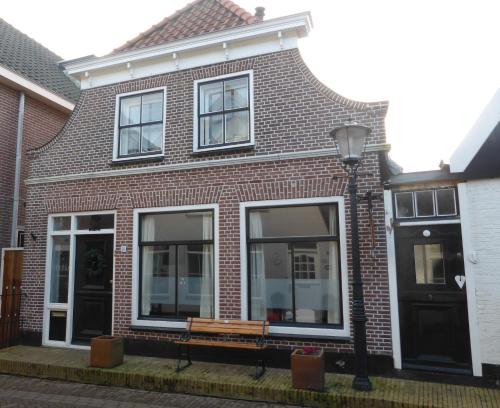 a brick house with a bench in front of it at B&B Bureau Warmoesstraat in Den Burg