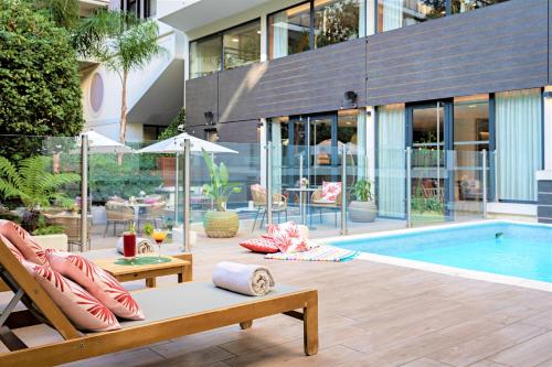 um pátio com uma piscina e cadeiras e um edifício em Hotel & Plage Croisette Beach Cannes Mgallery em Cannes