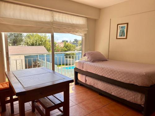 Schlafzimmer mit einem Bett und einem Tisch sowie einem Balkon in der Unterkunft Depto 5 in Concón