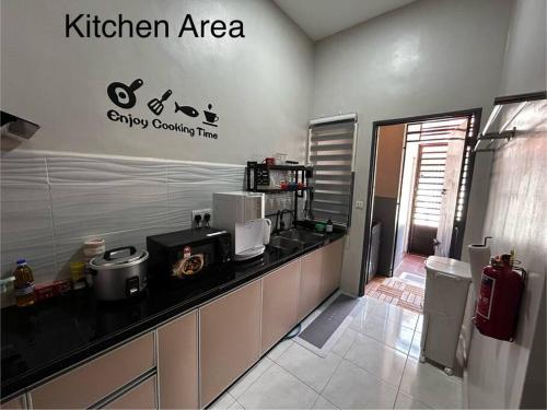 a kitchen with a counter with a kitchen area on the wall at Matsurika Guest House - Kulim in Kulim