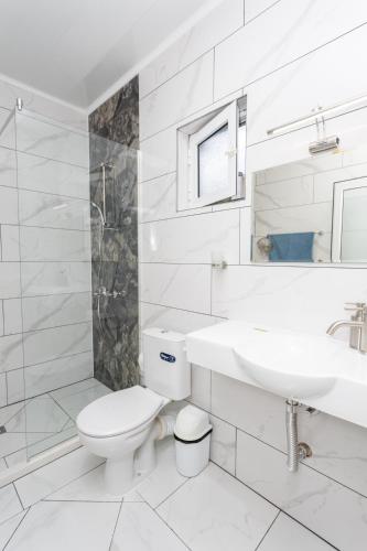 a white bathroom with a toilet and a sink at Guest rooms and apartments Desi in Balchik