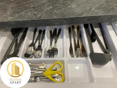 a drawer filled with utensils and a yellow scissors at Apartament Zielony in Tychy