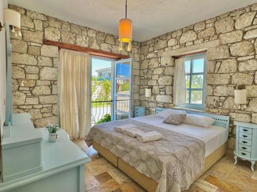 1 dormitorio con cama y pared de piedra en Dort Mevsim Alacati, en Alacati