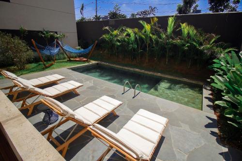 a swimming pool with chairs and a hammock on a patio at Blend Coliving One - 1 in Ribeirão Preto