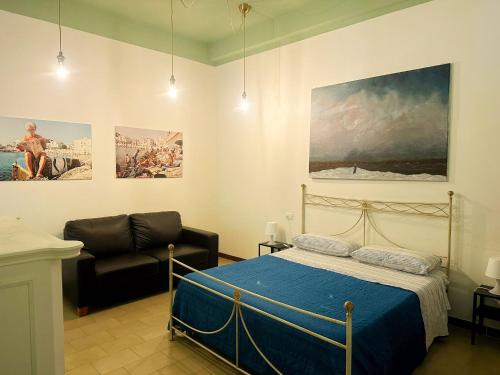 a bedroom with a bed and a couch and paintings at Il Mare di Giò in Monopoli