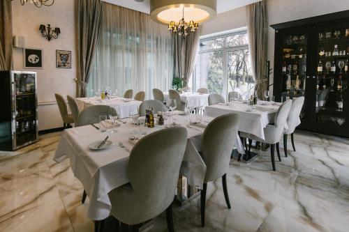 a restaurant with white tables and chairs and a chandelier at Hotel Heritage in Belgrade