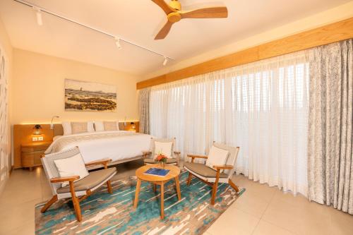 a bedroom with a bed and chairs and a ceiling fan at Ocean's Creek Beach Hotel in Balaclava