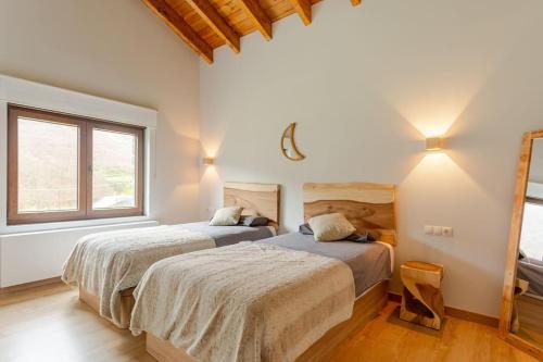 two beds in a room with two windows at Relax en Somiedo in La Peral