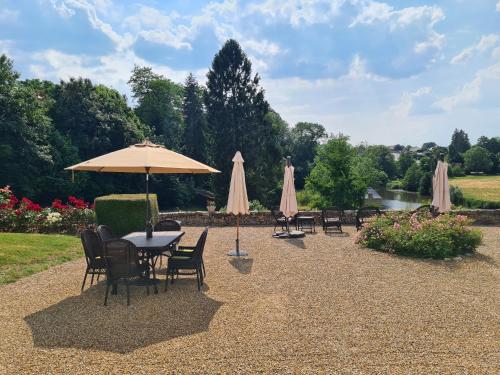 a patio with tables and chairs with umbrellas at Le Clos de Paris in Fresnay-sur-Sarthe