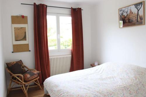 een slaapkamer met een bed, een stoel en een raam bij Maison et jardin à 5 min de Vannes in Meucon