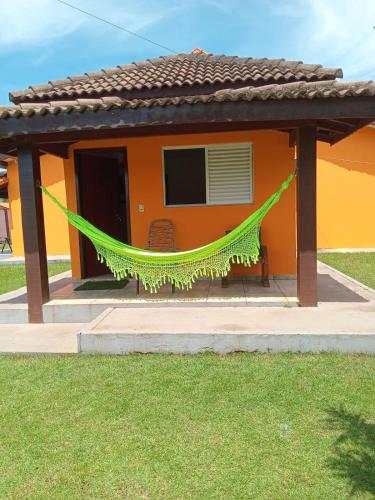 an orange house with a hammock in front of it at Pousada e restaurante Jardim do Cerrado MT in Nobres
