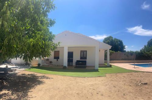 a small white house with a grass yard at Villa Marichu. Piscina, BBQ y a 15 min Puy du Fou in Totanés