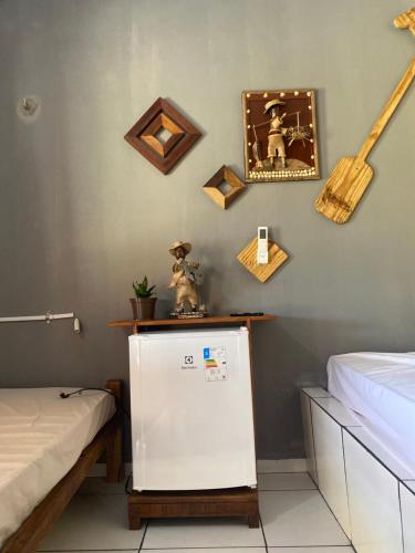 トゥトイアにあるPousada rancho sol nascenteの冷蔵庫が備わる客室で、壁に絵が飾られています。