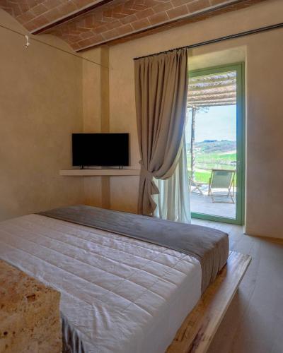 a bedroom with a bed and a tv and a window at Tenuta d'Arbia, Siena in Monteroni dʼArbia