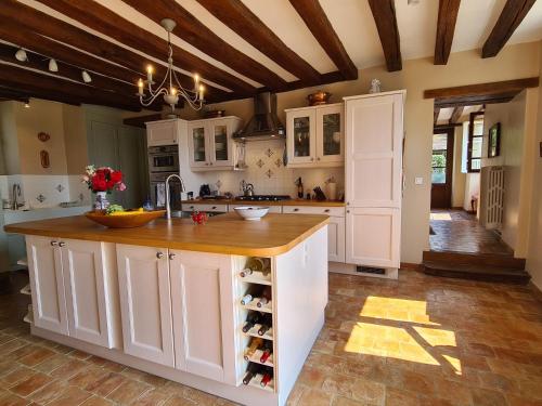 a kitchen with white cabinets and a counter with wine bottles at Le Clos de Paris in Fresnay-sur-Sarthe