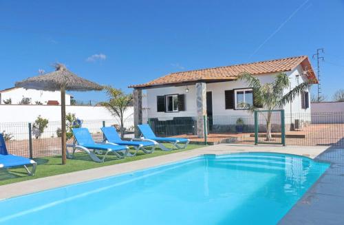 a swimming pool with blue chairs and a house at Alnoa I in Roche