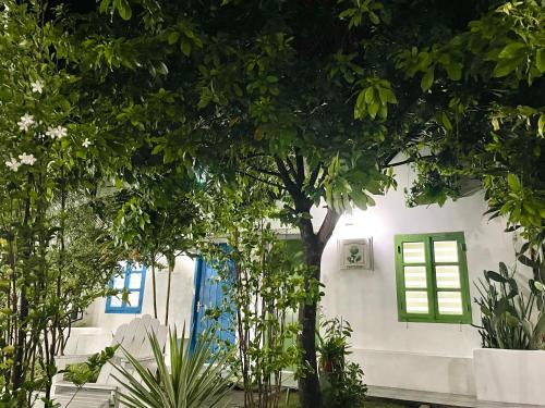 a white house with a green window and trees at Moonbeam Homestay & Mini-resort Mui Ne in Phan Thiet