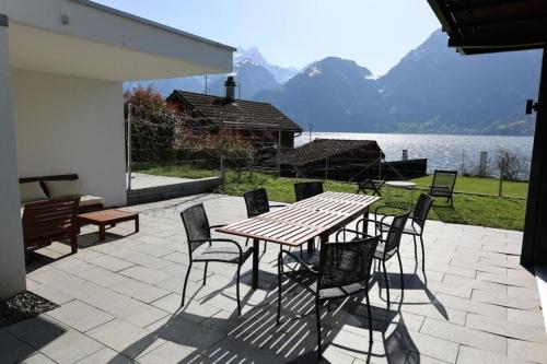 einen Holztisch und Stühle auf einer Terrasse neben einem See in der Unterkunft Ferienvilla am See 3 für 2-4 Personen in Sisikon