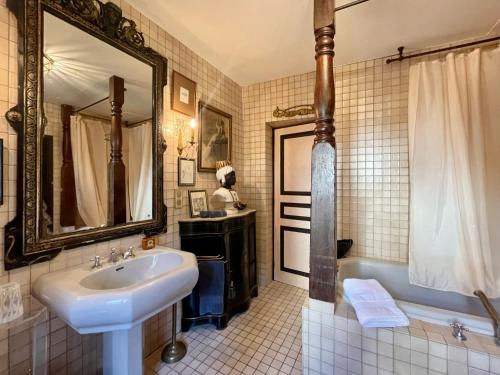 a bathroom with a sink and a tub and a mirror at La Maison des Chapitres in Forcalquier