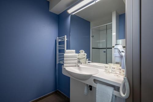 a bathroom with a white sink and a blue wall at ACE Hôtel Bordeaux Carbon Blanc in Carbon-Blanc