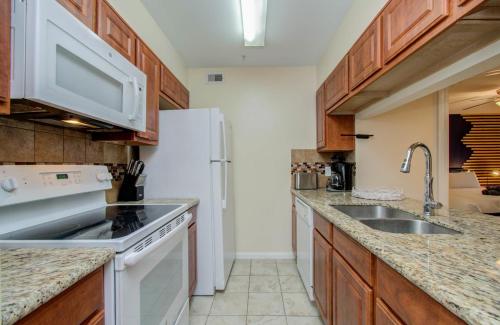 a kitchen with wooden cabinets and a white refrigerator at 3 Bedrooms Spacious Central Condo w Pool in Houston