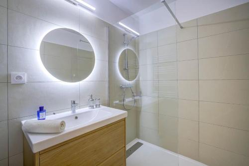 une salle de bain blanche avec un lavabo et un miroir dans l'établissement Studio vue mer, piscine - tennis, à Antibes